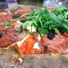 Pizza topped with salami, olives and fresh rocket salad leaves