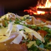 Pizza with rocket and Parmesan beside the wood fire